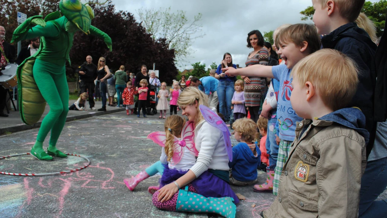 Community members creating colorful chalk art on pavement at family-friendly Adur Festival event
